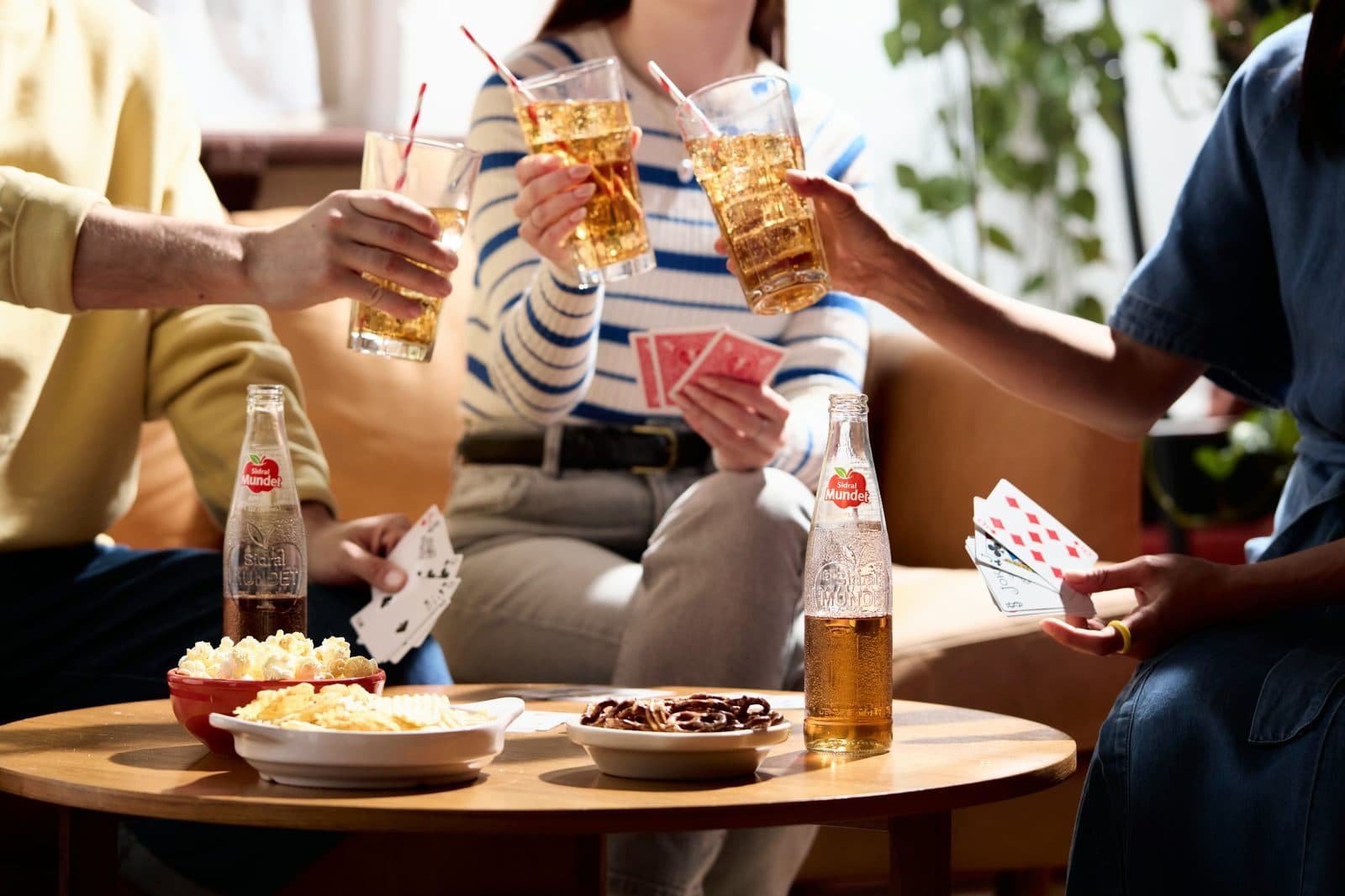 Friends playing a card game and enjoying drinks together around a table