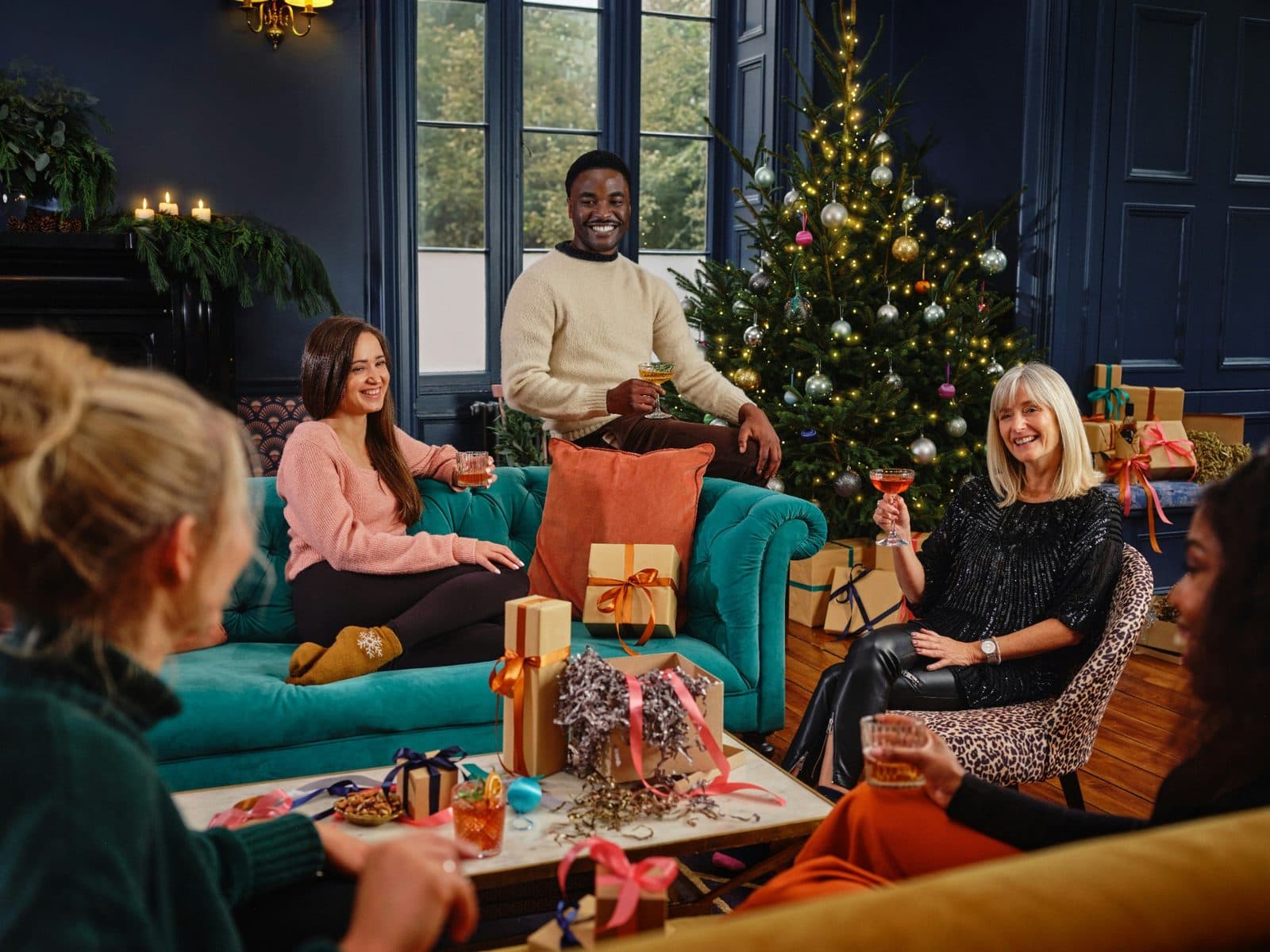 A group of people sitting together around a Christmas tree at a festive party